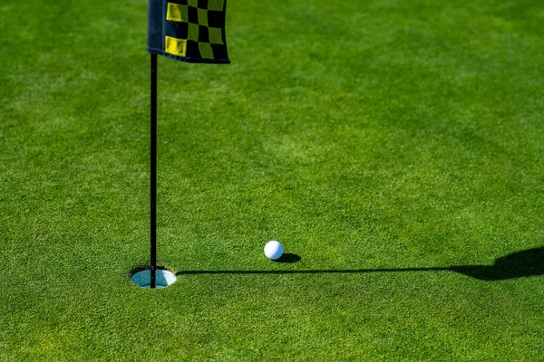 Golfgat. Golfbal op lip van beker op gras achtergrond. — Stockfoto