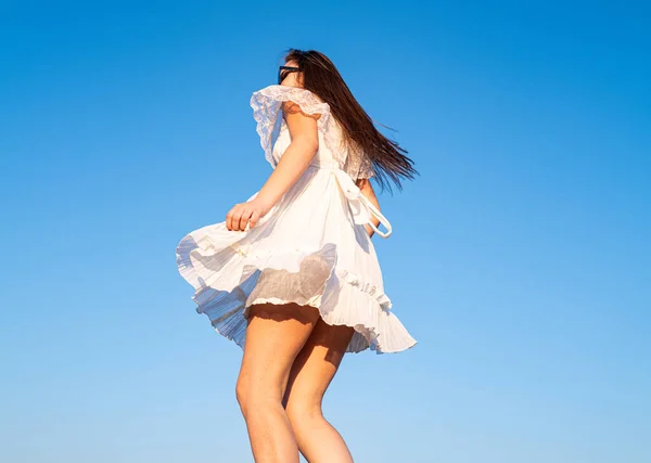 Chica de movimiento en vestido blanco en el cielo. Modelo femenino en un vestido de moda al aire libre. Mujeres despreocupadas afuera. — Foto de Stock