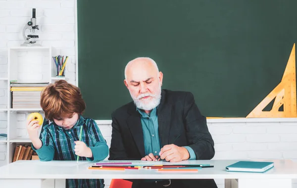 Un nonno e un figlio stanno imparando in classe. Studente e tutoraggio concetto di istruzione. Torniamo a scuola. Vecchi e Giovani. Giorno di insegnanti. — Foto Stock