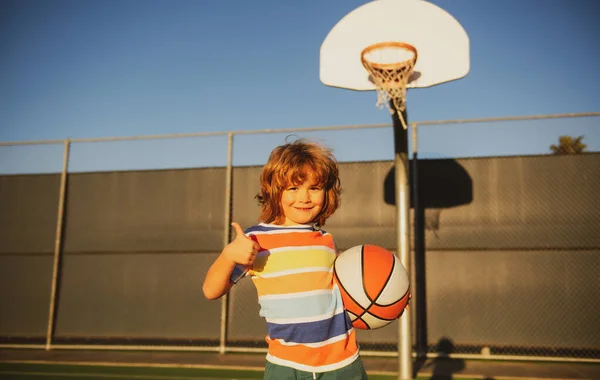 Glad liten pojke unge spelar basket på lekplatsen. — Stockfoto