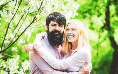 Yeşil bahar sonbahar çifti. Şefkatli aşk duyguları. Sevgi dolu bir adam ve kadın bahar çiçekli bir parkta yürüyorlar..