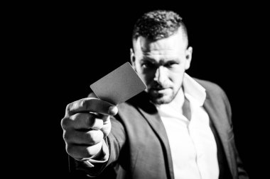 Kredi kartını veren genç bir adam kameraya bakıyor, siyah arkaplan. İş adamı kredi kartı ya da banka kartı ile ödeme yapar. İş adamı kredi kartıyla ödeme yapar..