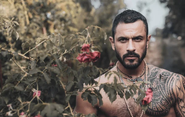Frumos latino musculare om gata de Ziua Îndrăgostiților Fericit. Bărbat în trandafiri roșii și femei — Fotografie, imagine de stoc