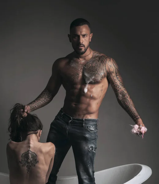 Dominante en el juego sexual juegos previos. Pareja tatuada. Hombre y mujer tatuados se divierten en el baño y él lava su hermosa espalda. Concepto dominante . — Foto de Stock