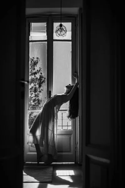 Belle fille aux cheveux longs. Elle danse joyeusement. La fille est habillée en tenue de nuit. Jeune femme debout près du balcon. Modèle de mode en sous-vêtements sexy . — Photo