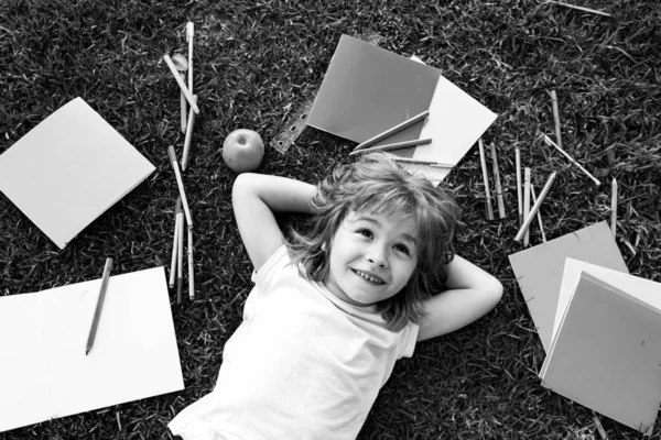 Schuljunge in der Natur für den Sommer. Ein Kind liegt im Gras. Traum vom Schulbesuch. — Stockfoto
