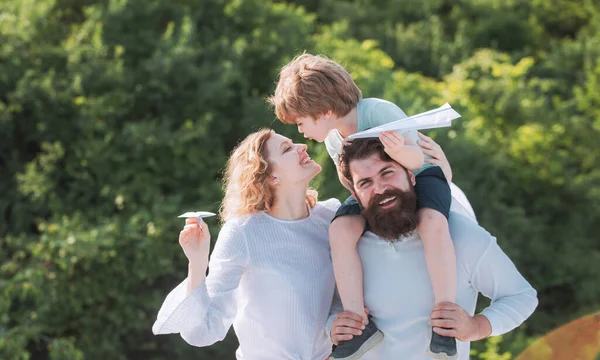 Anne baba ve oğul. Baba anne ve oğlu dışarıda oynuyorlar. Köy hayatı. Yaz istihkakı. Sevimli küçük çocuk kağıt uçak tutuyor. Mutlu bir aile. Ebeveynler ve çocuk.