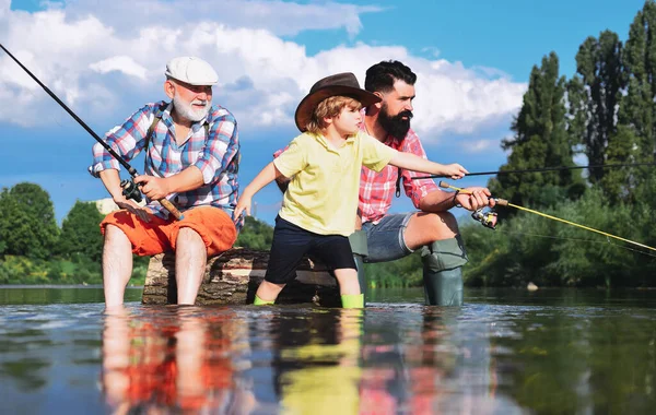 Fishing became a popular recreational activity. Grandfather with son and grandson having fun in river. Men hobby. Family fishermen fishing with spinning reel. — Stock Photo, Image