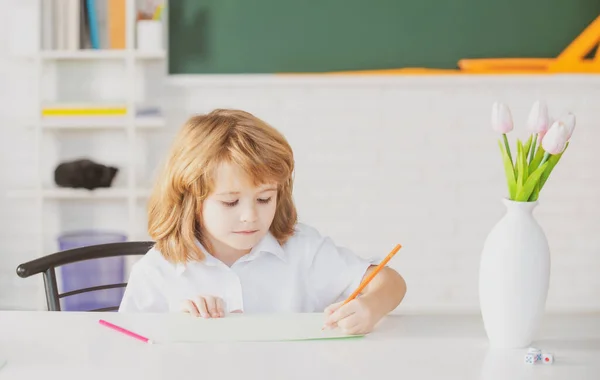 Un élève qui donne des cours à la maison. Un écolier écrit quelque chose dans un livre et s'assoit à table en classe. Première année. — Photo