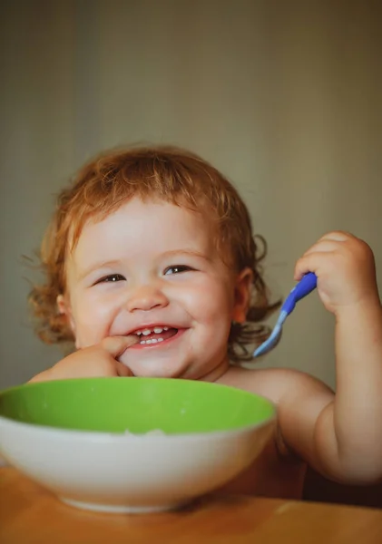Dítě jí polévku v kuchyni s nádobím a lžící. Spouštění dětského jídla. — Stock fotografie