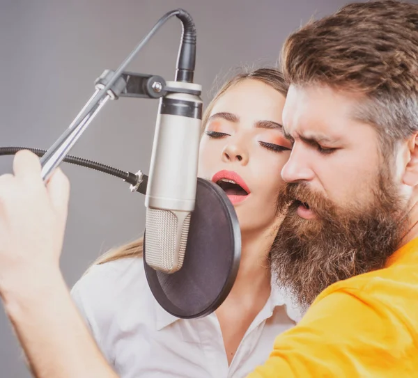 Zpěvák pár hraje píseň s mikrofonem při nahrávání v hudebním studiu. — Stock fotografie