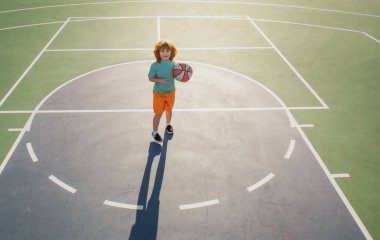Basketbol çocuk oyunu. Sevimli küçük çocuk basket topu tutuyor ve sayı yapmaya çalışıyor..