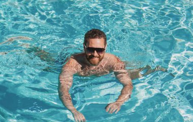 Aktif hafta sonu. Yüzme havuzu. Yaz tatili. Adam havuzda yüzüyor. Yaz havuzu tatil köyü.