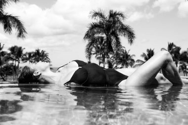 Güzel manken yaz aylarında egzotik deniz manzarasında havuzda rahatlar..