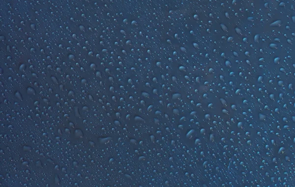 Cseppállagú. Nedves csepp víz üveg kék háttér. — Stock Fotó