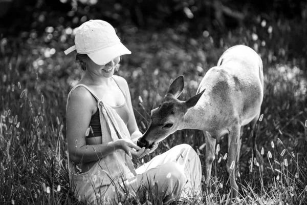 Unidade com a natureza. Rapariga alimenta veados bambi. Conceito de animais selvagens. Mulher a alimentar o Fawn. Animais no parque. — Fotografia de Stock