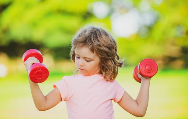 Kind turnt im Park. Aktiver Junge, gesunder Lebensstil. Sportkind mit starker Bizeps-Muskulatur trainiert Hantel. — Stockfoto