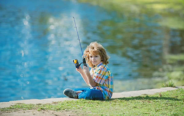 Vissersjongen. Jongen met spinner bij River. Kind aan steiger met staaf. — Stockfoto