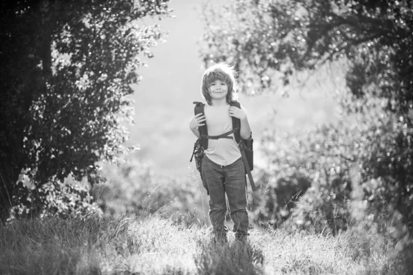 Leuke jongen met wandelspullen in de bergen. Kind wandelaar met rugzak wandeling in heuvels achtergrond. — Stockfoto