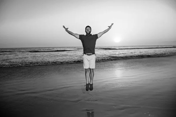 Мужчина прыгает по пляжу, силуэт на закате. Удивительный вид на закатный пляж. — стоковое фото
