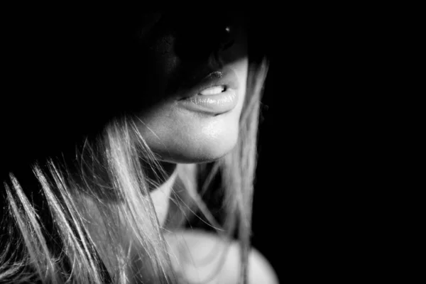 Junge Frau posiert im Studio vor schwarzem Hintergrund. Licht und Schatten auf den Lippen. Modeporträt einer schönen Frau mit dunklem Licht im Gesicht. — Stockfoto