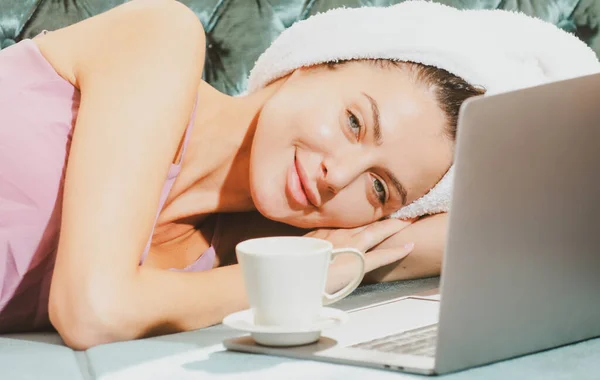 Piękna zmysłowa młoda kobieta z kawą i laptopem w piżamie ciesząca się porannym wypoczynkiem w sypialni w domu. — Zdjęcie stockowe