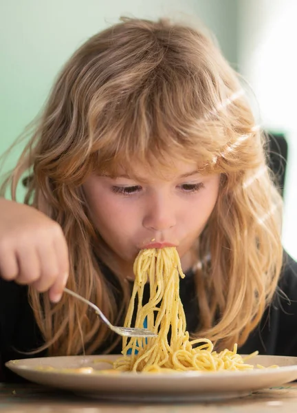 Chutné jídlo, špinavé dítě, které jí špagety. Dítě si dá snídani. Chutná dětem snídaně. Péče o děti a dětství. Detailní záběr portrét legrační dítě jíst nudle těstoviny. — Stock fotografie