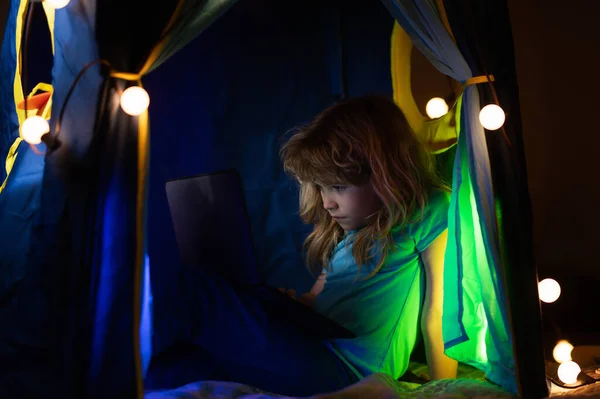 Child sitting in home tent playing with laptop. — Stock Photo, Image