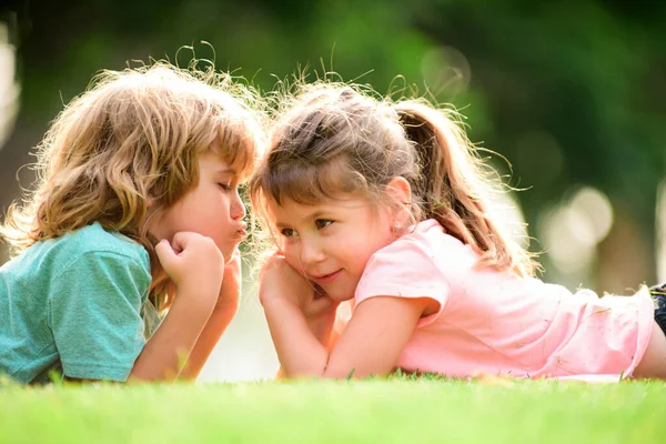 Two little children hug and kiss each other in summer garden. Kids couple in love. Friendship and childhood. Children on pirnic. Shy girl. — Fotografia de Stock