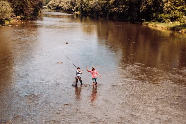 Retrato de pesca alegre homem sênior. Pescadores avós e filhos. Jovem e um velho pescando por spinnings no rio ou lago. — Fotografia de Stock