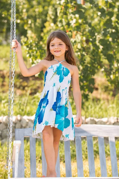 Cute little girl on a swing. Smiling child playing outdoors in summer. Happy kids swinging at the park. Happy kid having fun outdoors. — Stock Photo, Image