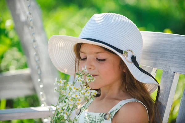 Küçük kız yeşil arka bahçedeki çiçekleri kokluyor. Yaz otlağındaki sevimli çocuk ve çiçek kokusu. Çocuklarla güzel bir bahar bahçesinde yaz eğlencesi.. — Stok fotoğraf