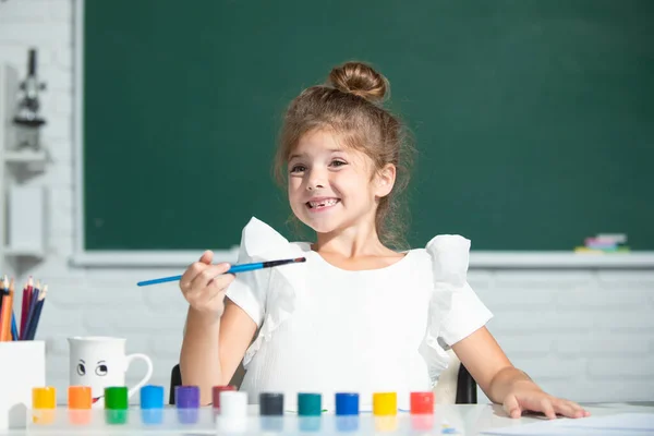 Aranyos kis óvodás lány rajzol az iskolában. Gyermek lány festett az általános iskolában. Vicces gyerekek érzelmei. — Stock Fotó