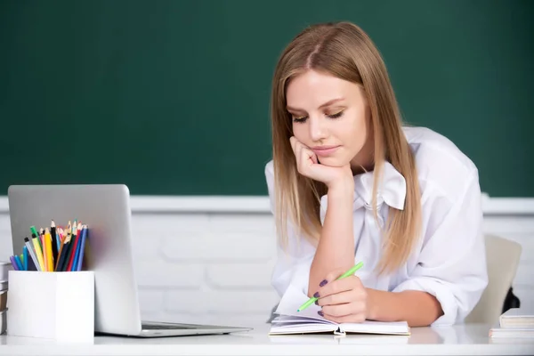 Kvinnlig student på lektionsföreläsning i klassrum på gymnasiet eller högskolan. Studentutbildningskoncept. Kvinnliga studerande funderar på kursarbete vid universitetet. — Stockfoto