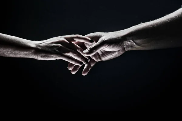 Due mani si allungano a vicenda, sfondo nero. Coppia innamorata che tiene Hads, da vicino. Aiutare mano, sostegno, amicizia. — Foto Stock