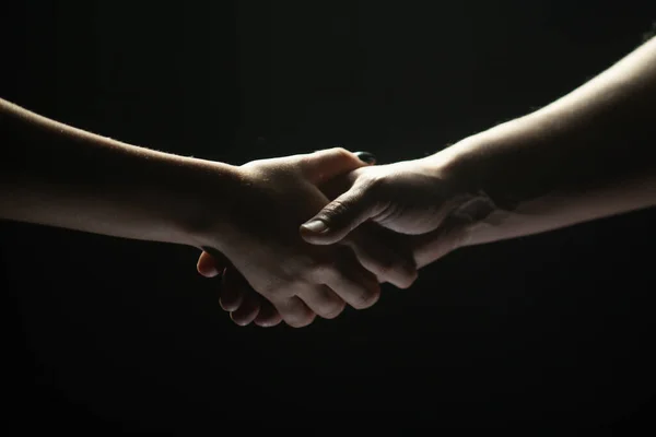 Händerna gestikulerar på svart bakgrund. Ge en hjälpande hand. Stöd och hjälp, överenskommelse. Händerna på två personer av räddning. Hjälpande hand utsträckt för frälsning. Handslag mellan de två parterna. — Stockfoto