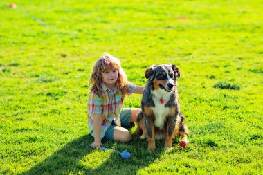 Cute child with a puppy dog, outdoor summer. The boy plays with the dog in park in the summer.