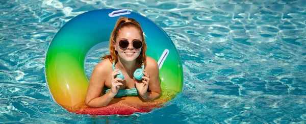 Letní prázdniny. Užívám si opálení. Žena v plavkách na nafukovacím kroužku ve sluchátkách bazénu. Nápis pro záhlaví, kopírovací prostor. Plakát pro web design. — Stock fotografie