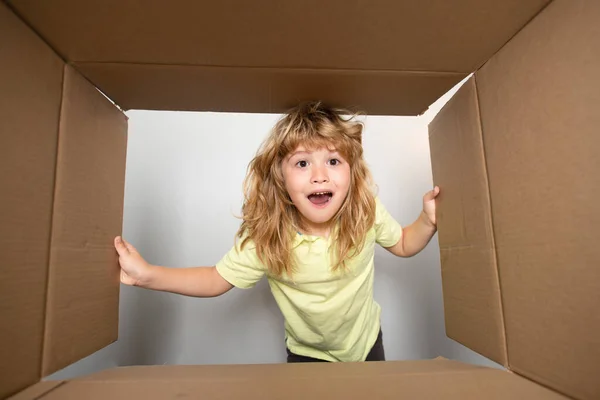 Bambino ragazzo aprire una scatola di cartone e guardando dentro, disimballaggio concetto, sorpresa unboxing. Concetto di imballaggio o disimballaggio dei pacchi. — Foto Stock