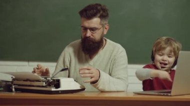 Eski ve genç kavramları. Teknoloji nesli. Baba oğul gelişimi. Gençler yaşlı yetişkinlere karşı. Baba ve oğul eski daktilo ve dizüstü bilgisayarda yazıyor..