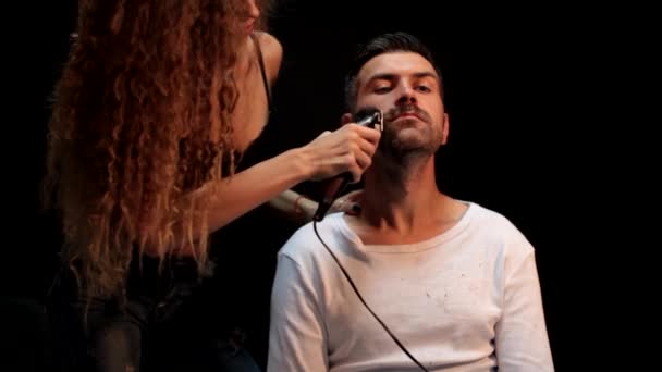 Cutting long beard. Woman hairdresser cuts beard handsome man at barbershop. Beard care. — Wideo stockowe