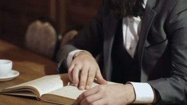 Bearded man in classic suit read book in library. Classic literature. English classic style. Man reading book in bookshelf.