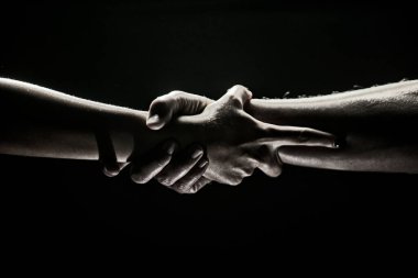Eller siyah arka planda hareket ediyor. Yardım eli uzatıyorum. Destek ve yardım, kurtuluş. Kurtarma sırasında iki kişinin güçlü ve güçlü görüntüsü. Kurtuluşa uzanan ellere yardım ediyorum. Sıkı tutun..