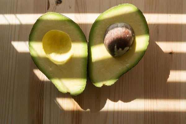 Aguacate sobre fondo de madera. Fruta del aguacate. Frutas crudas alimentos verdes saludables. Mitad aguacate. — Foto de Stock