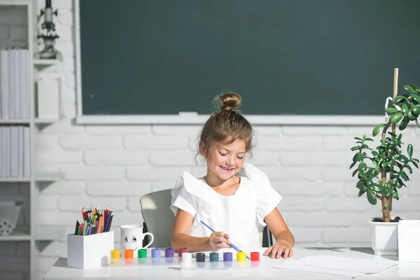 Девочка в школе рисует красками. Детский творческий подход. Детский творческий рост. — стоковое фото