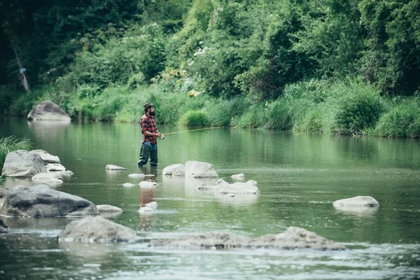 Jeune homme barbu pêchant dans un lac ou une rivière. Pêche au mouche. — Photo