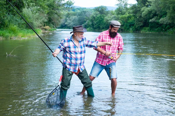 Padre e figlio maturo pescatore pesca con una canna da pesca sul fiume. Felice uomo eccitato amici. — Foto Stock