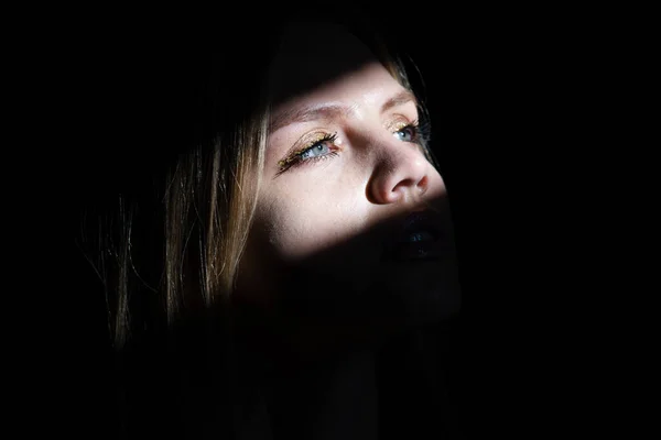 Porträtt av elegant kvinna med ljus på en svart bakgrund. Vackert kvinnligt ansikte i mörkret. — Stockfoto