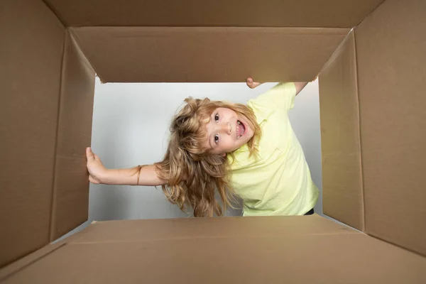 Kid unpacking and opening carton box, and looking inside with surprise face. Open big box. — Foto de Stock