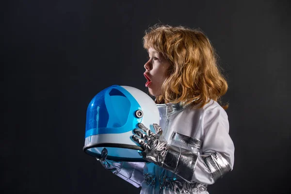 Cute little excited boy spaceman child in space suit holding helmet on black background. — ストック写真